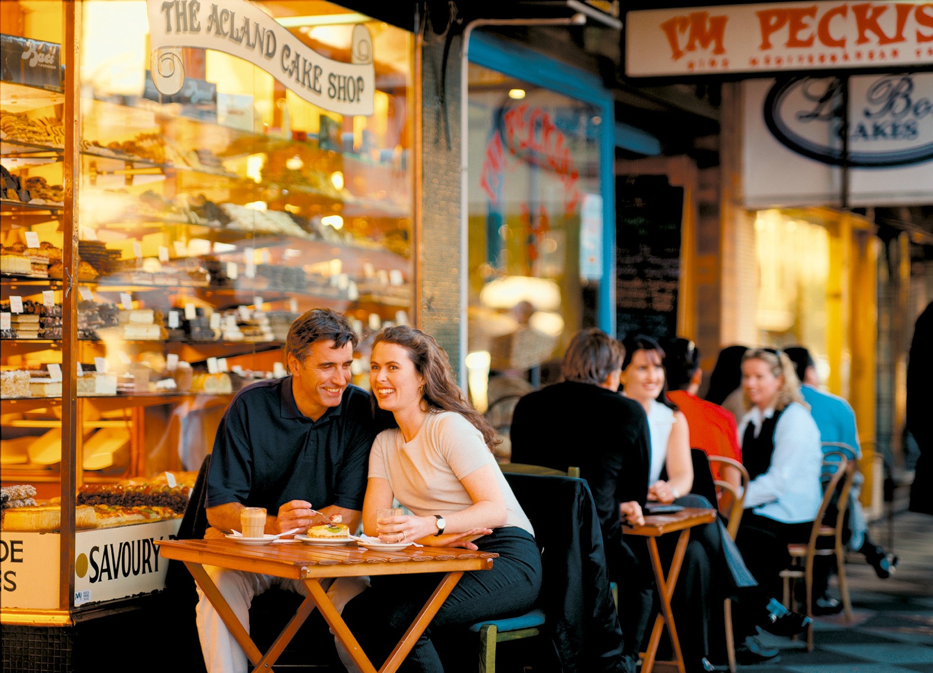 Bilden visar ett par som sitter på ett café. Kylmontrar för restaurang och café är praktiska vid försäljning av mat och dryck.